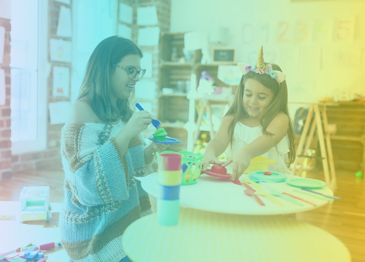 A rainbow-filtered image of a woman in a sweater playing with a young girl wearing a unicorn horn headband