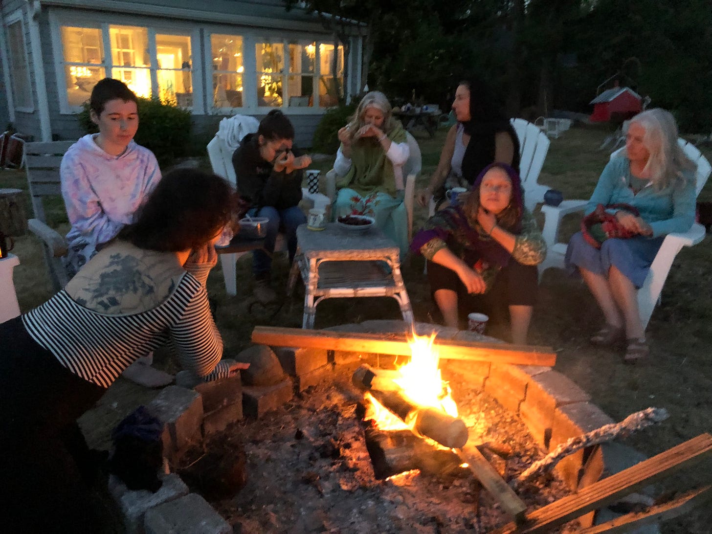 8 women gather around a fire