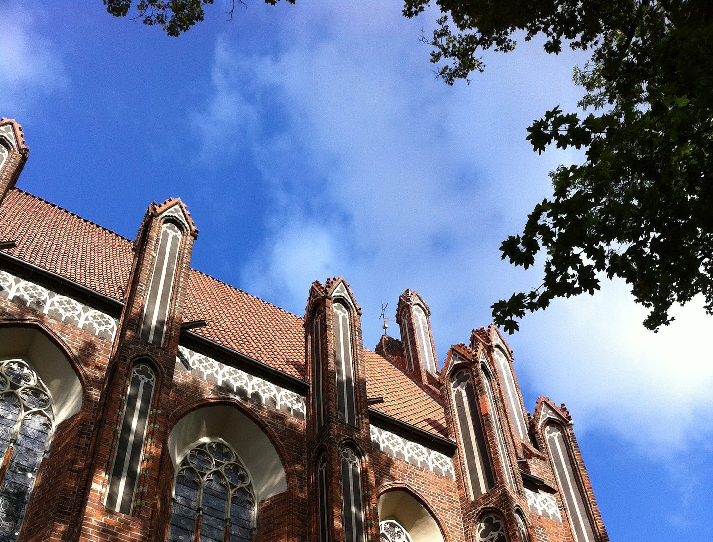 scorcio di una chiesa di Toruń con rami di albero e cielo con nuvole