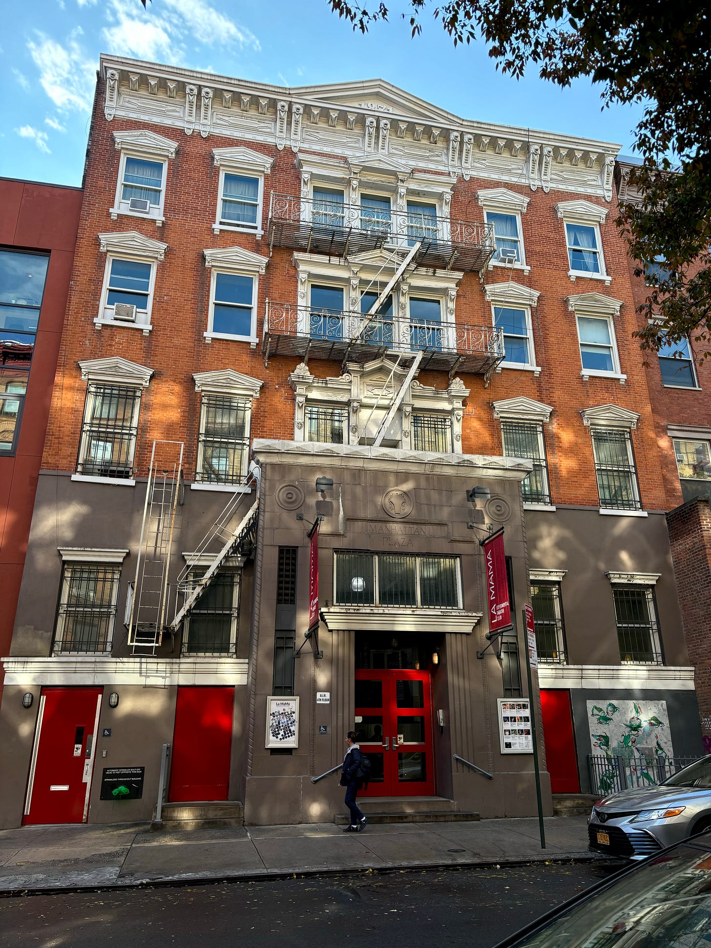 66 East 4th, a brick building with a gray stone entry that is engraved Manhattan Plaza.