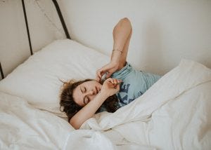 a beautiful young woman waking up in bed.