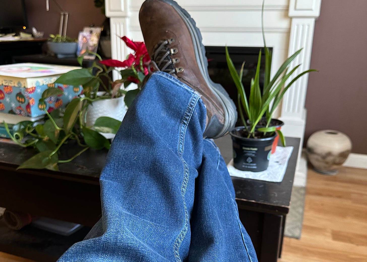 A first person POV of a man in jeans and work boots with his feet up on a coffee table