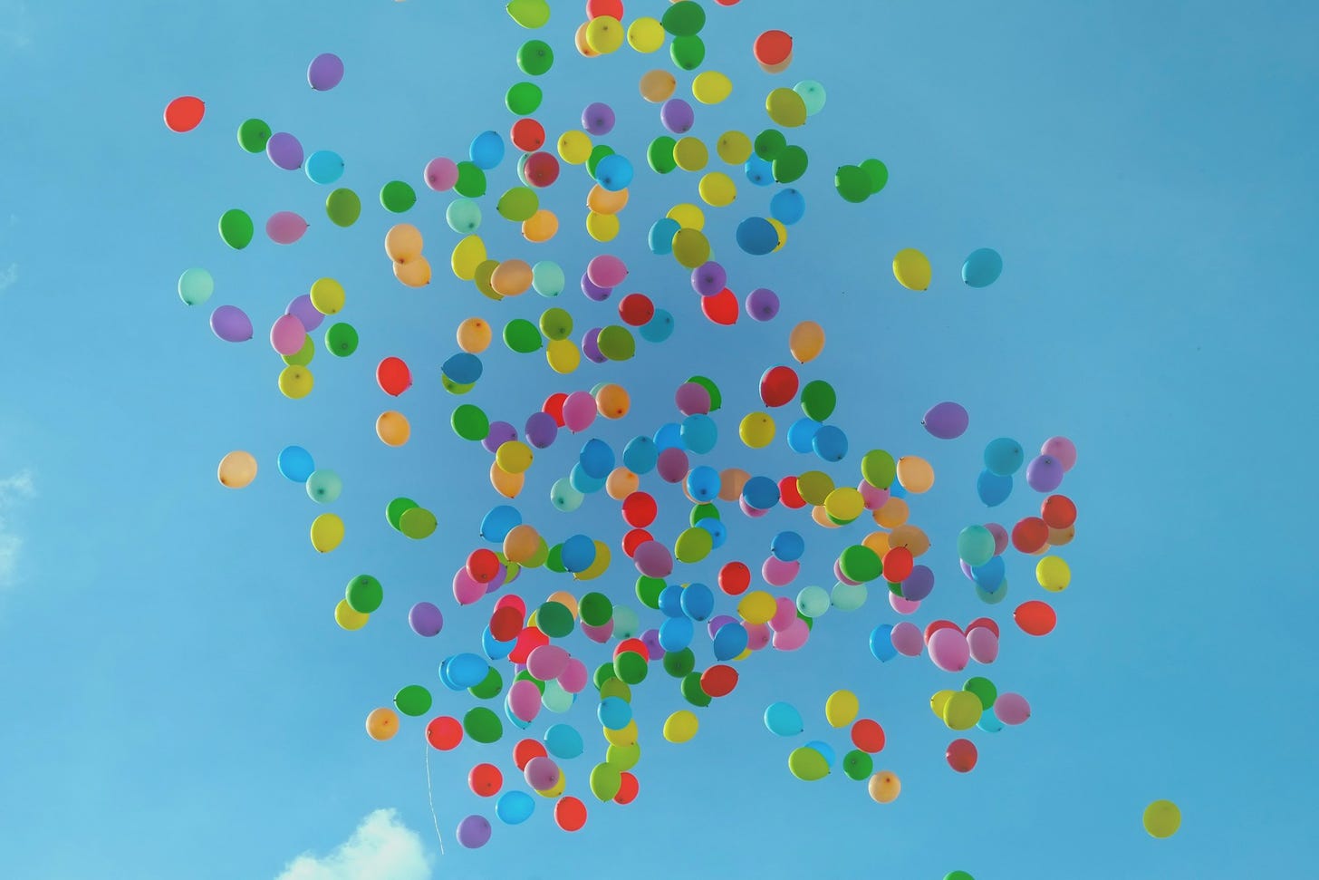 A blue sky with a cloud of balloons