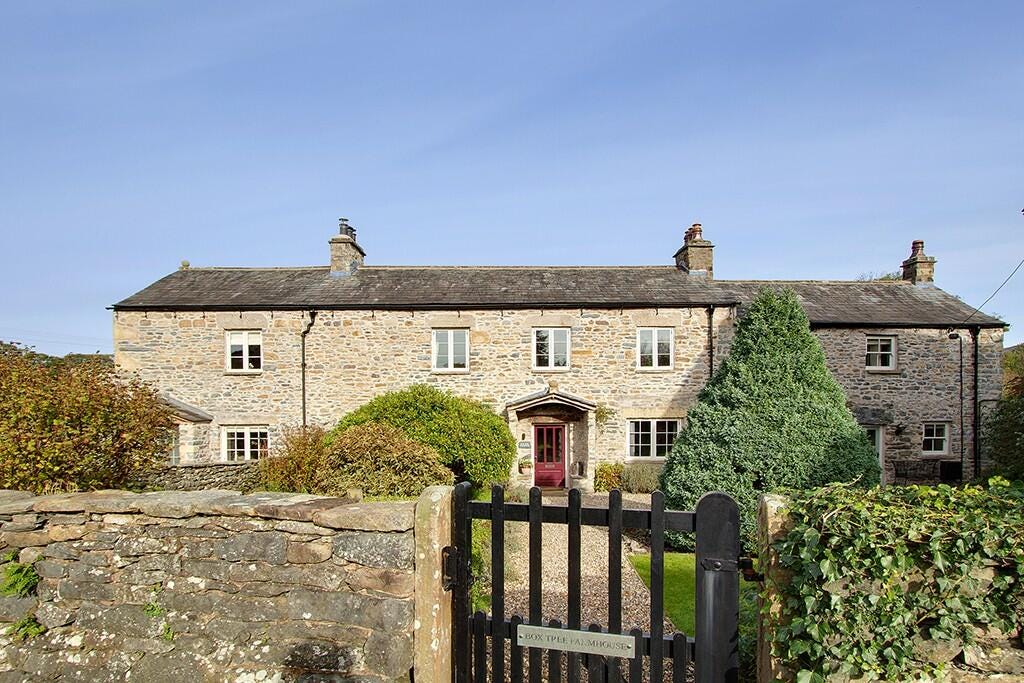 Front elevation of a stone farmhouse with a little wooden gate. It's delightful