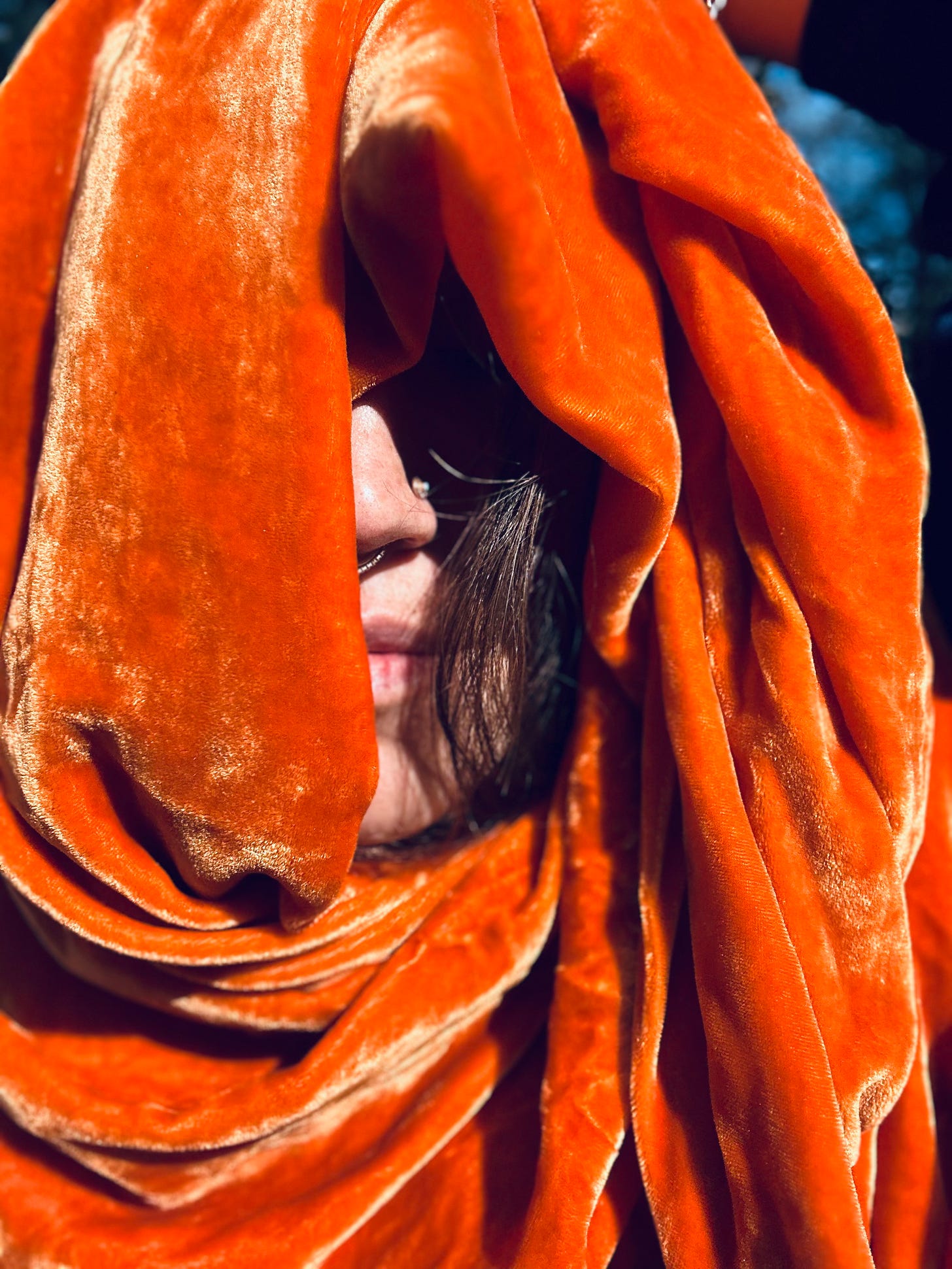 a selfie of me wrapped in an orange velvet scarf with my nose and nose ring just barely peeking out