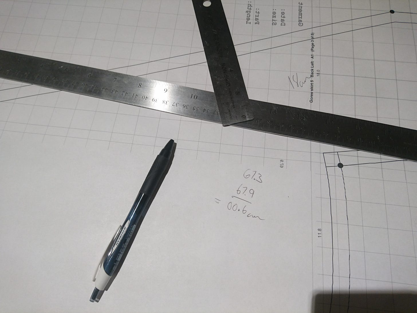 pattern paper with rulers and a pen on top, and some quick math drawn on the paper
