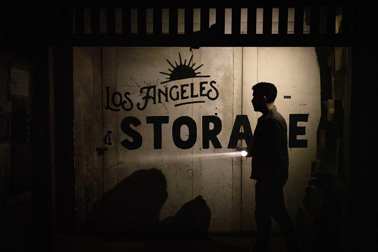 A person walks past a corridor with a sign for Los Angeles Storage
