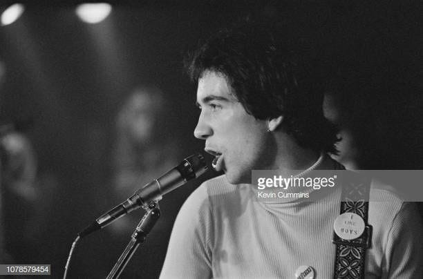 Pete Shelley of Buzzcocks wearing a "I Like Boys" pin on his guitar strap.