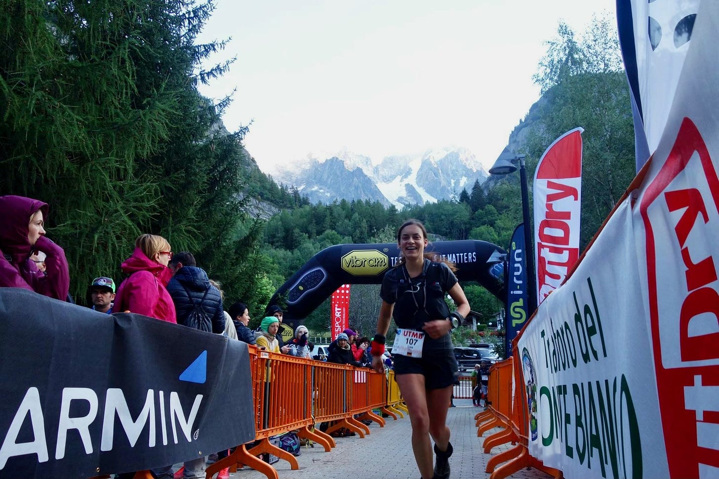 Female runner at UTMB smiling in front of a mountain range