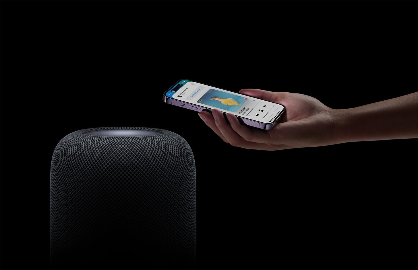 The new HomePod in black linking up with an iPhone 13 Pro to share music.
