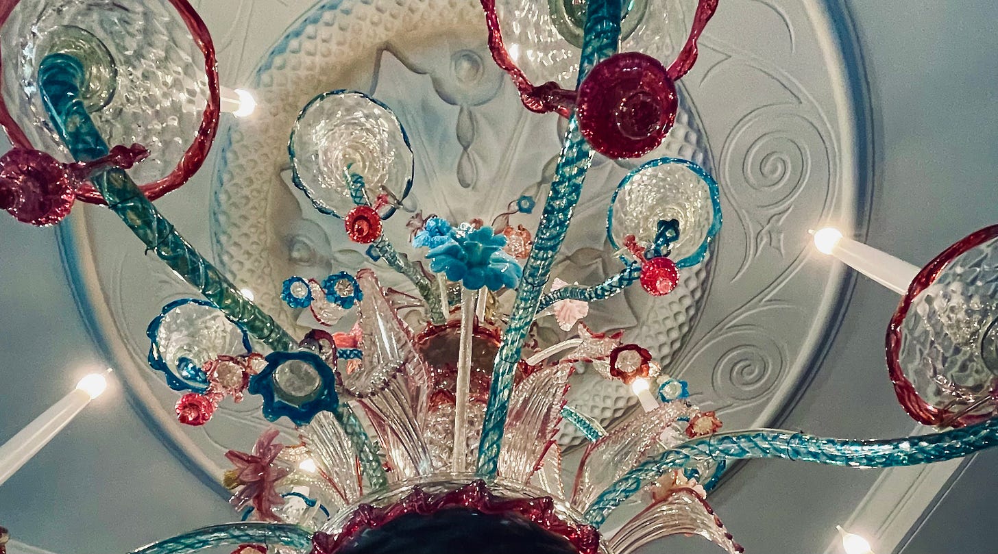 Looking upwards towards and white, red, pink and blue murano glass chandelier 