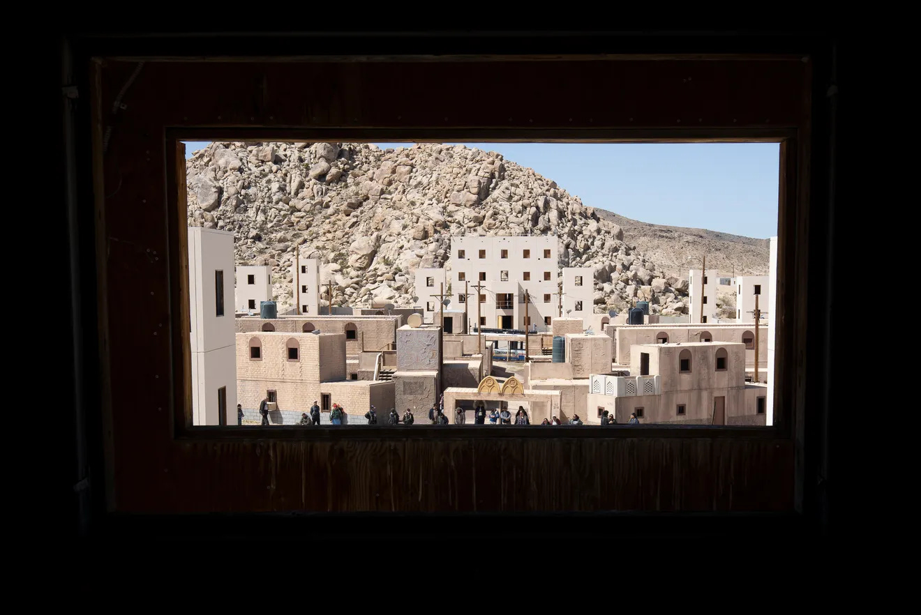 A view out of a window into a fake town constructed from shipping containers in the Mojave desert.
