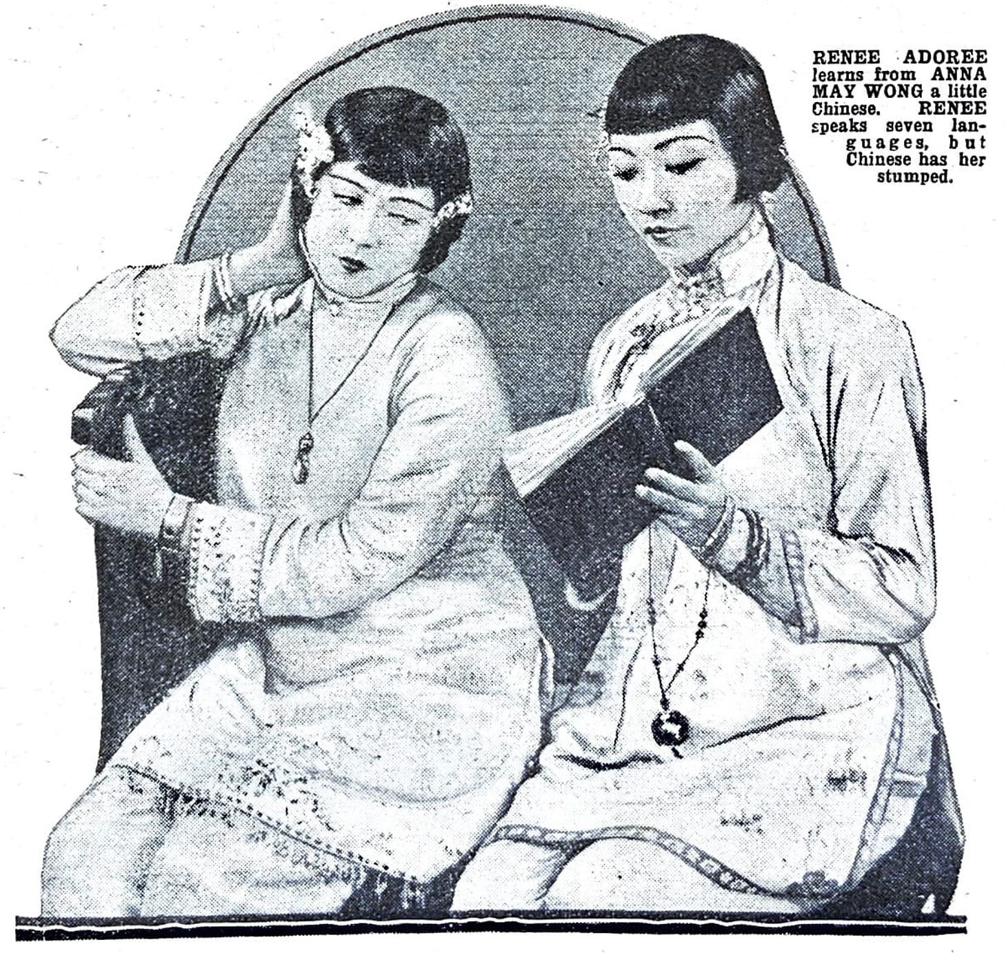 caption on clipping says: "Renee Adoree learns from Anna May Wong a little Chinese." The actresses are in Chinese dress and sit next to each other as AMW holds a book open.