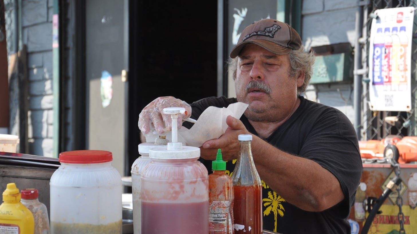 Randy Pollack prepares a hot dog at his cart.