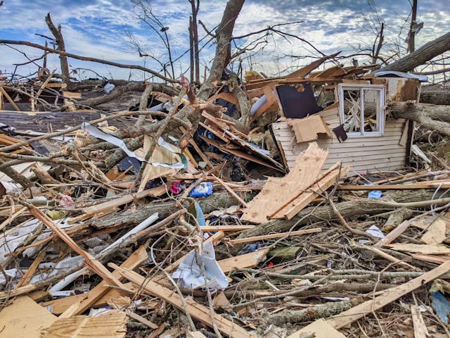 a house decimated by a tornado, you can only tell it was a house because part of one wall is standing, the rest is bits of boards, scraps of clothing, and pieces of debris