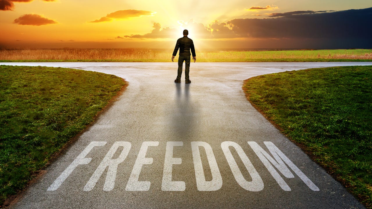 A man standing on a road with the word "Freedom" on it.