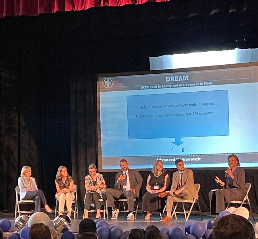 A panel of speakers on stage in front of a slide that reads “Default middle school pathway ends in Algebra I”