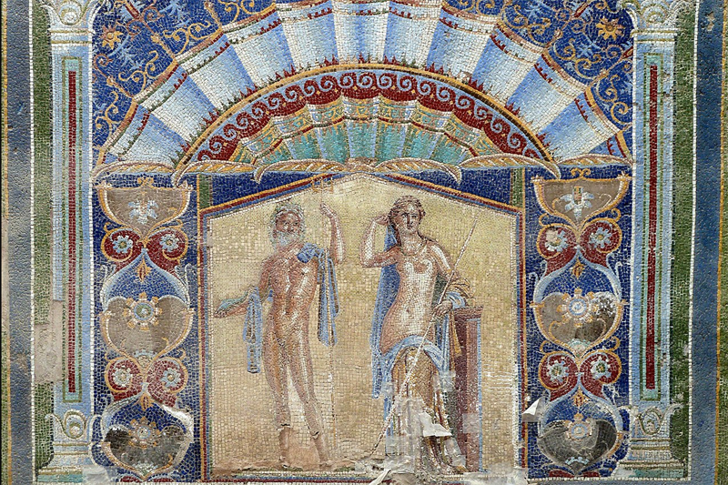 Large formal mosaic showing an exceptionally beautiful man and woman—by Roman standards—naked but for elegantly draped shawls, surrounded by large stylized flowers and winecups and symmetric designs like waves of the sea in rich colors of gold and blue and burgundy.