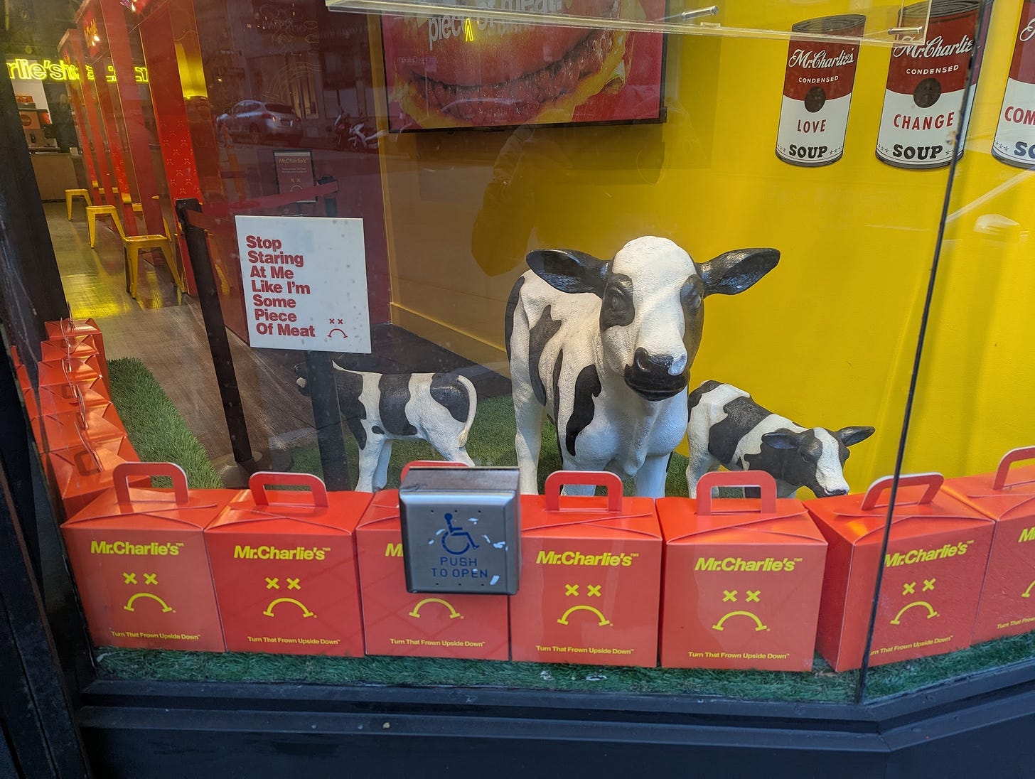 Window display at MrCharlie's restaurant in San Francisco. In the foreground, a lineup of red boxes displays the suggestion to "Turn That Frow Upside Down"