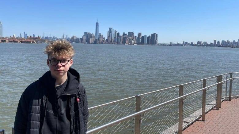 a boy posing in front of a New York City's skyline