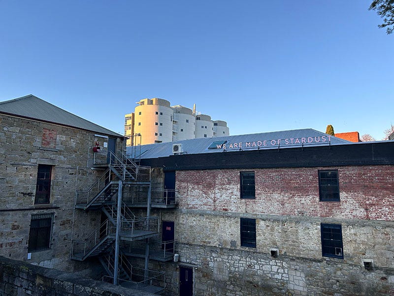 Buildings in Hobart on a sunny winter’s day. A neon sign on one building reads ‘We are made of stardust’. 