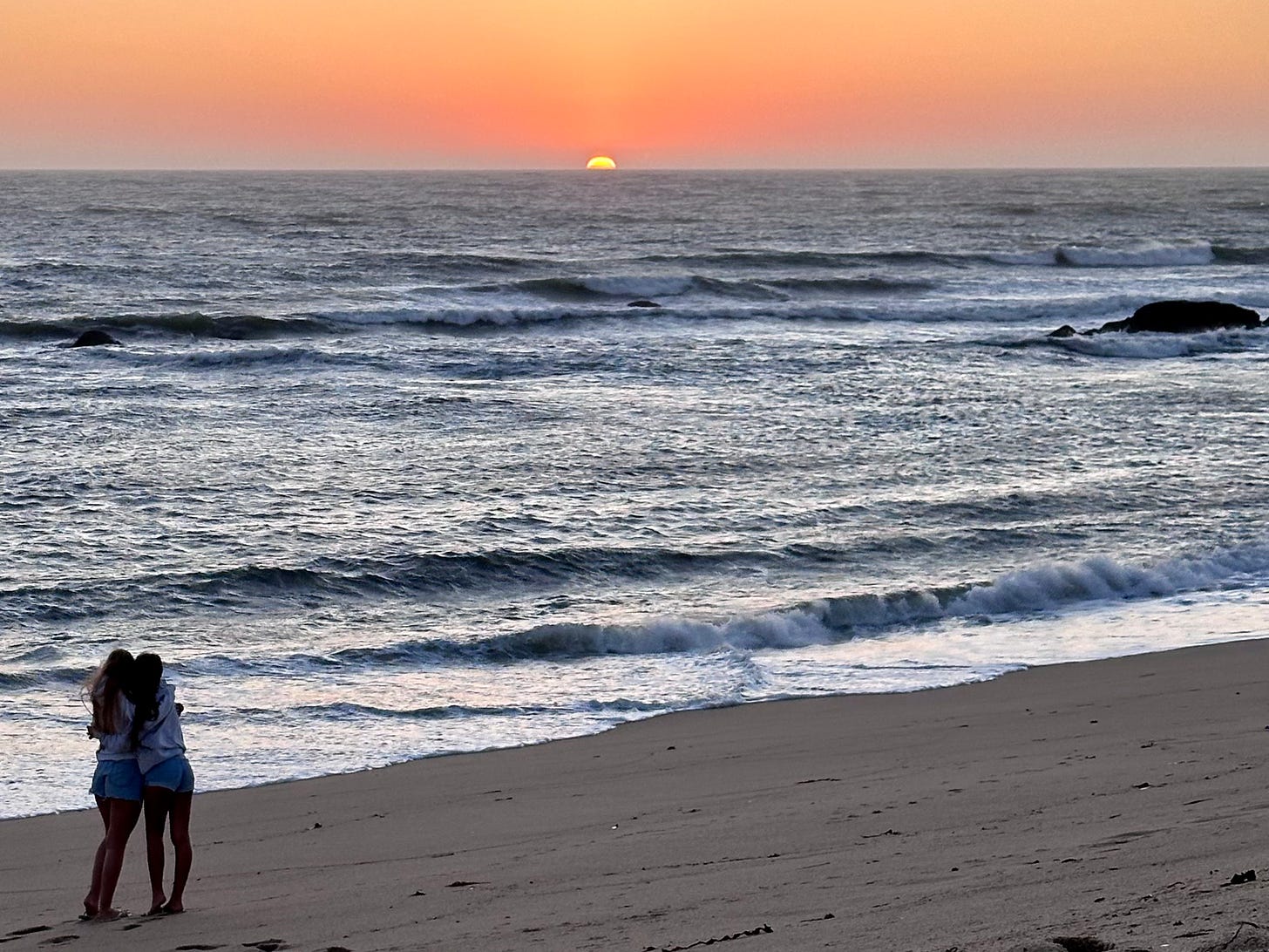 Two girls embracing watching the sunset in Portugal