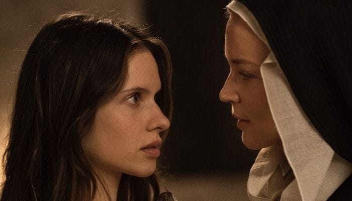 This may contain: two women in nun costumes looking at each other