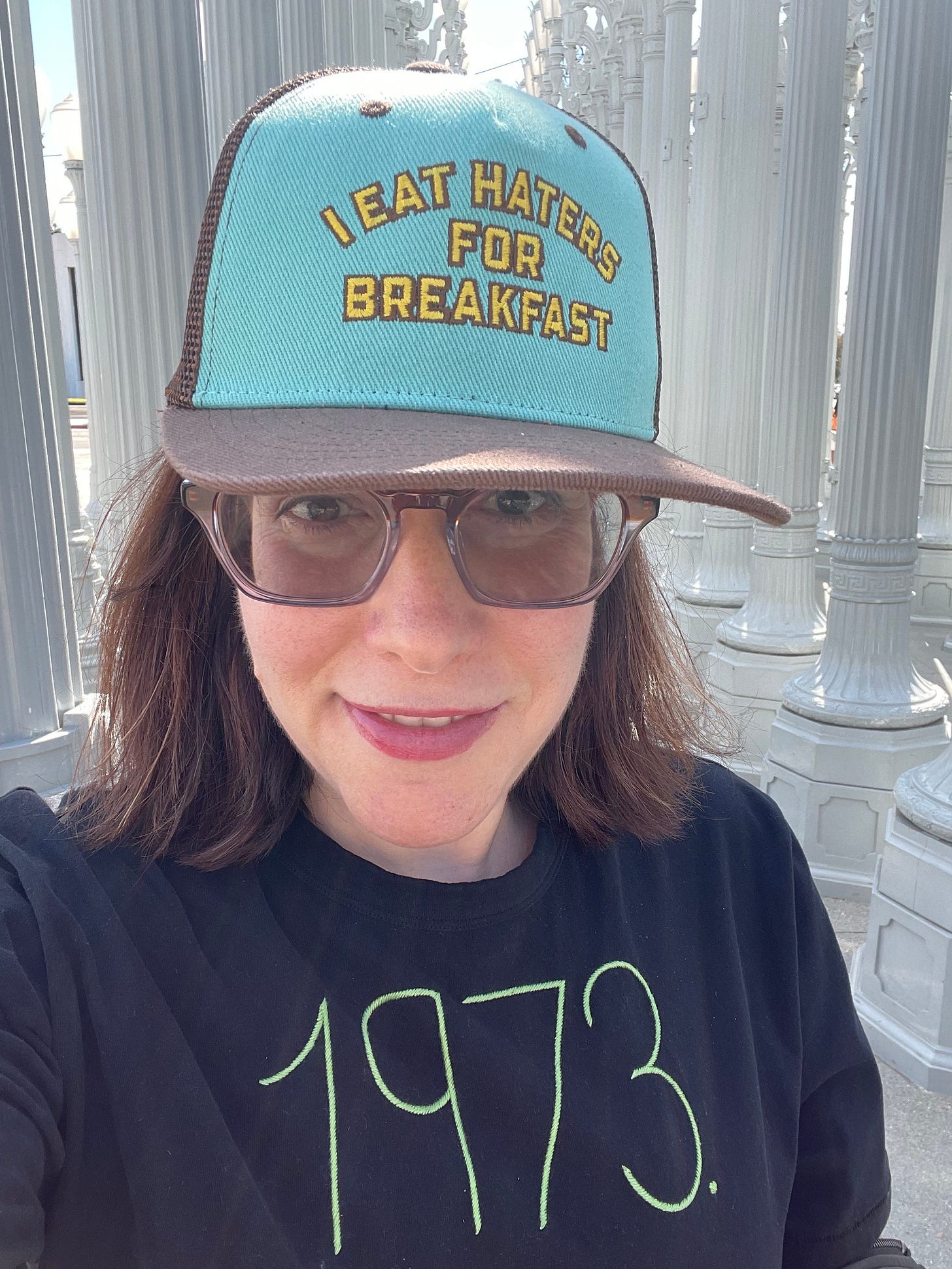 Rachel Kramer Bussel wearing I Eat Haters for Breakfast baseball cap and 1973 t shirt outside LACMA