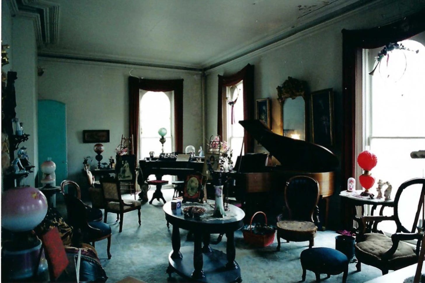 Photo of parlor in Victorian house with antique chairs, lamps, tables, and other tchotchkes