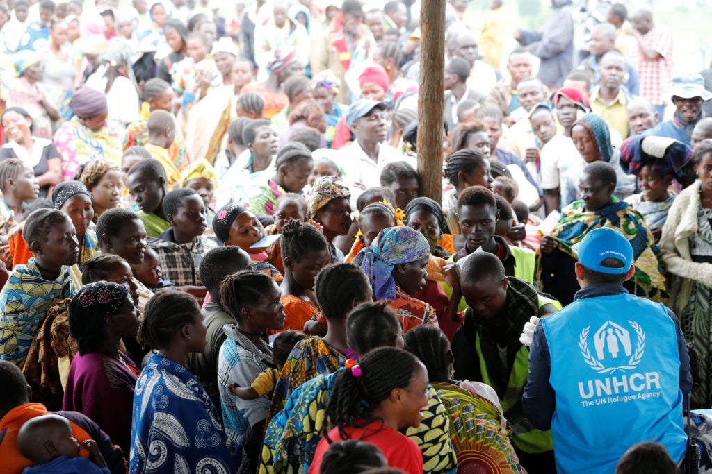 A UN worker monitors Congolese refugees who fled from the Democratic Republic of Congo by boat across Lake Albert, upon ar...