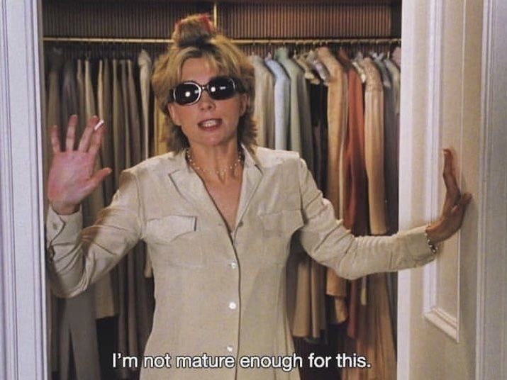 This may contain: a woman wearing sunglasses standing in front of a closet full of clothes with her hands up