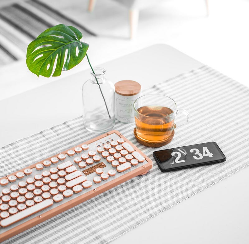 desk area with plant and keyboard and drink near clock with time reading 2:34