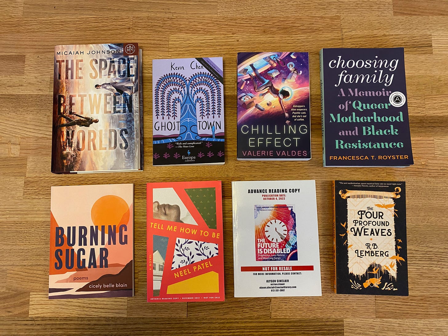 The eight listed books laid out in two rows of four on a wooden counter.
