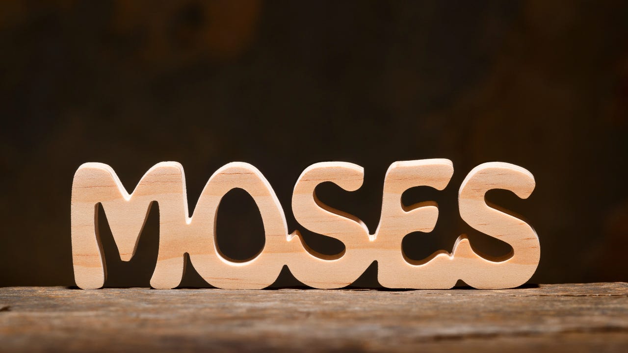 The word "Moses" in wooden carved letters.