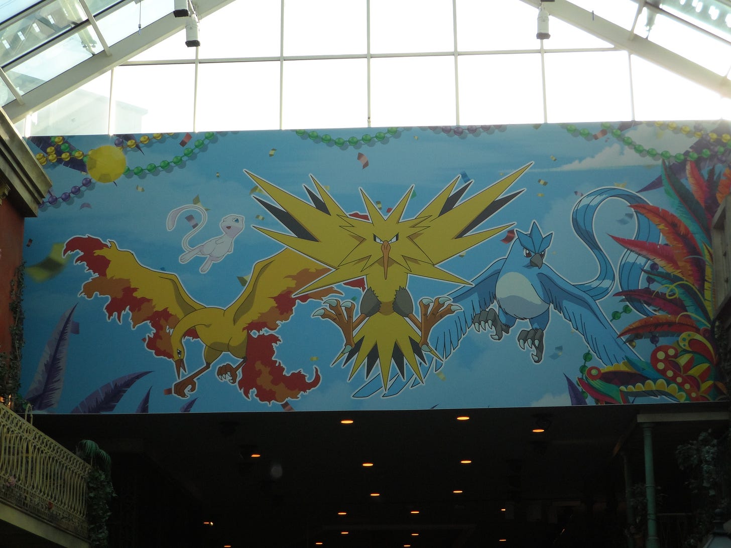 A huge banner above one of the hallways, featuring Articuno, Zapdos, Moltres, and Mew