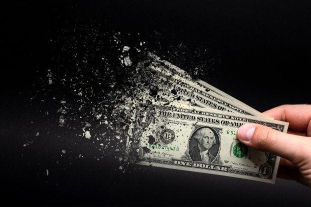 Inflation, dollar hyperinflation with black background. One dollar bill is sprayed in the hand of a man on a black background. The concept of decreasing purchasing power, inflation