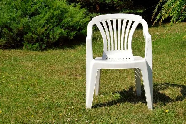 A white plastic chair in a garden.