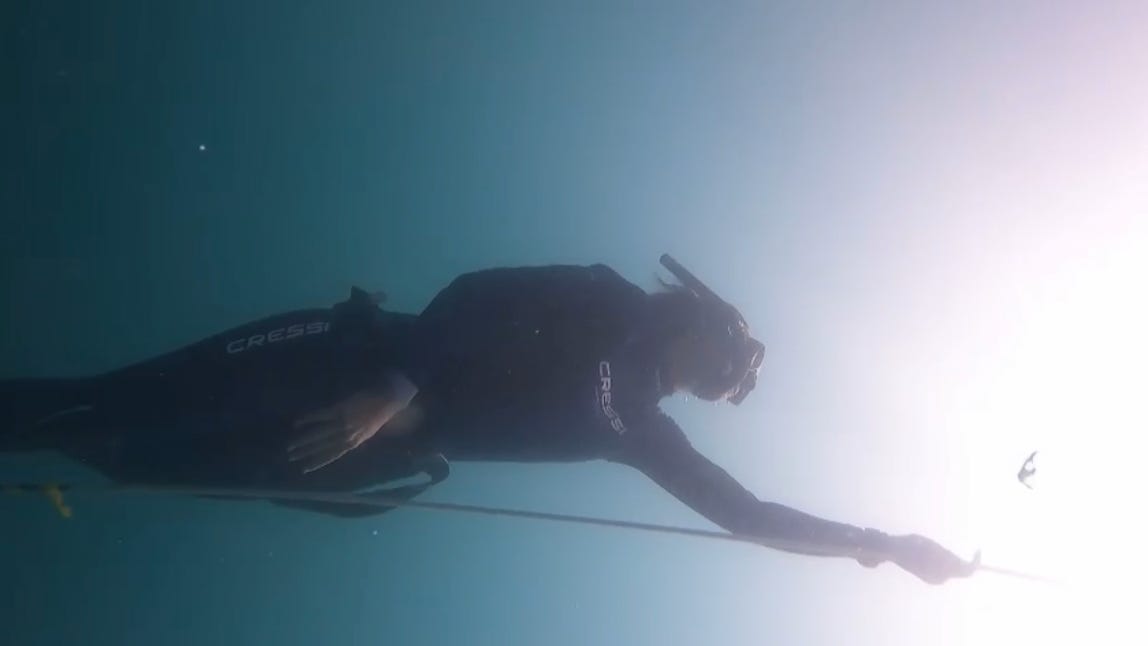Woman underwater holding rope.