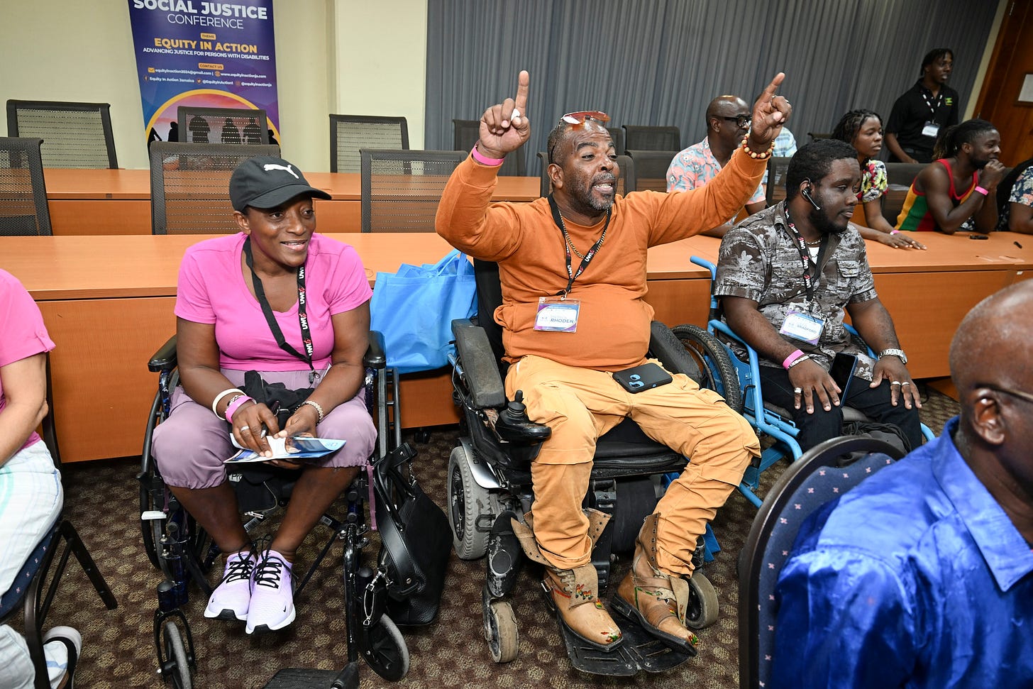 A group of Black organizers, 3 who use manual wheelchairs, at a conference.