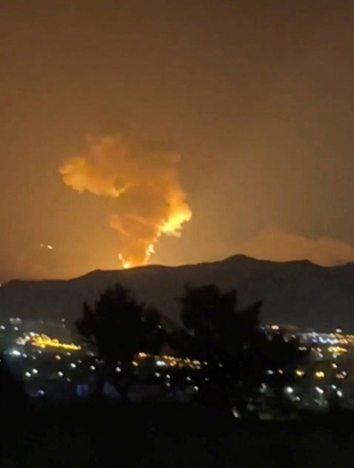 Smoke rising over a city at night during the Israel-Iran air war.