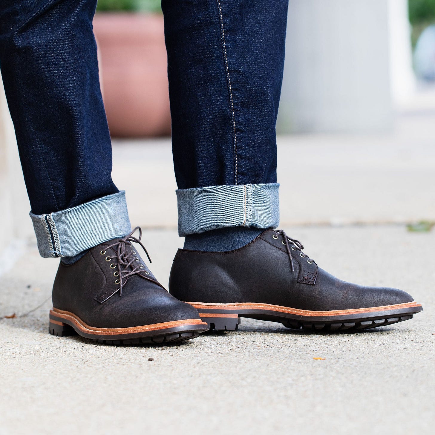 A close-up of brown leather shoes paired with rolled-up dark jeans, showcasing a casual yet stylish look. A close-up of brown leather shoes paired with rolled-up dark jeans, showcasing a casual yet stylish look.