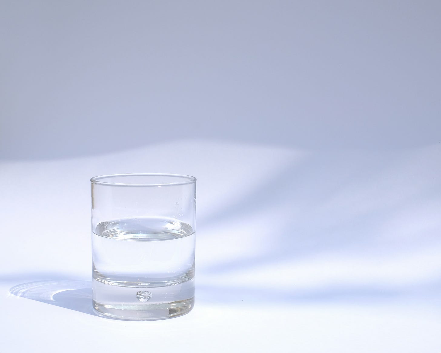 Half a glass of water set against a white backdrop.
