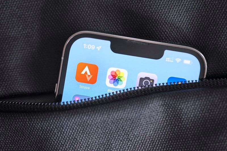 A photo of the Strava app icon on a screen of a smartphone partially sticking out of someone's pocket.