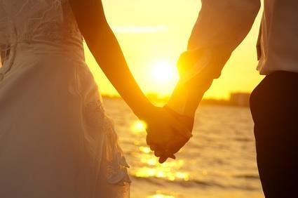 Holding Hands Young adult male groom and female bride holding hands on beach at sunset. WONG SZE ...