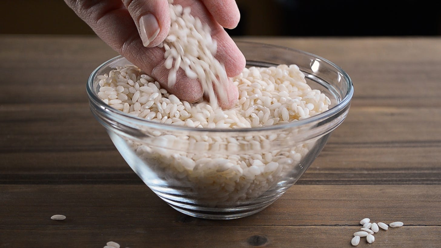 Close up shot of uncooked medium grain rice running through fingers.