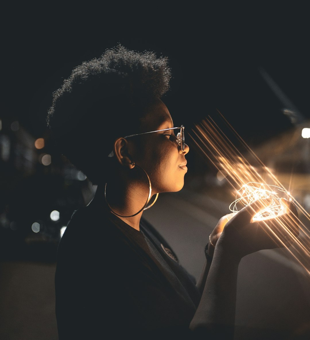 woman standing and holding string lights