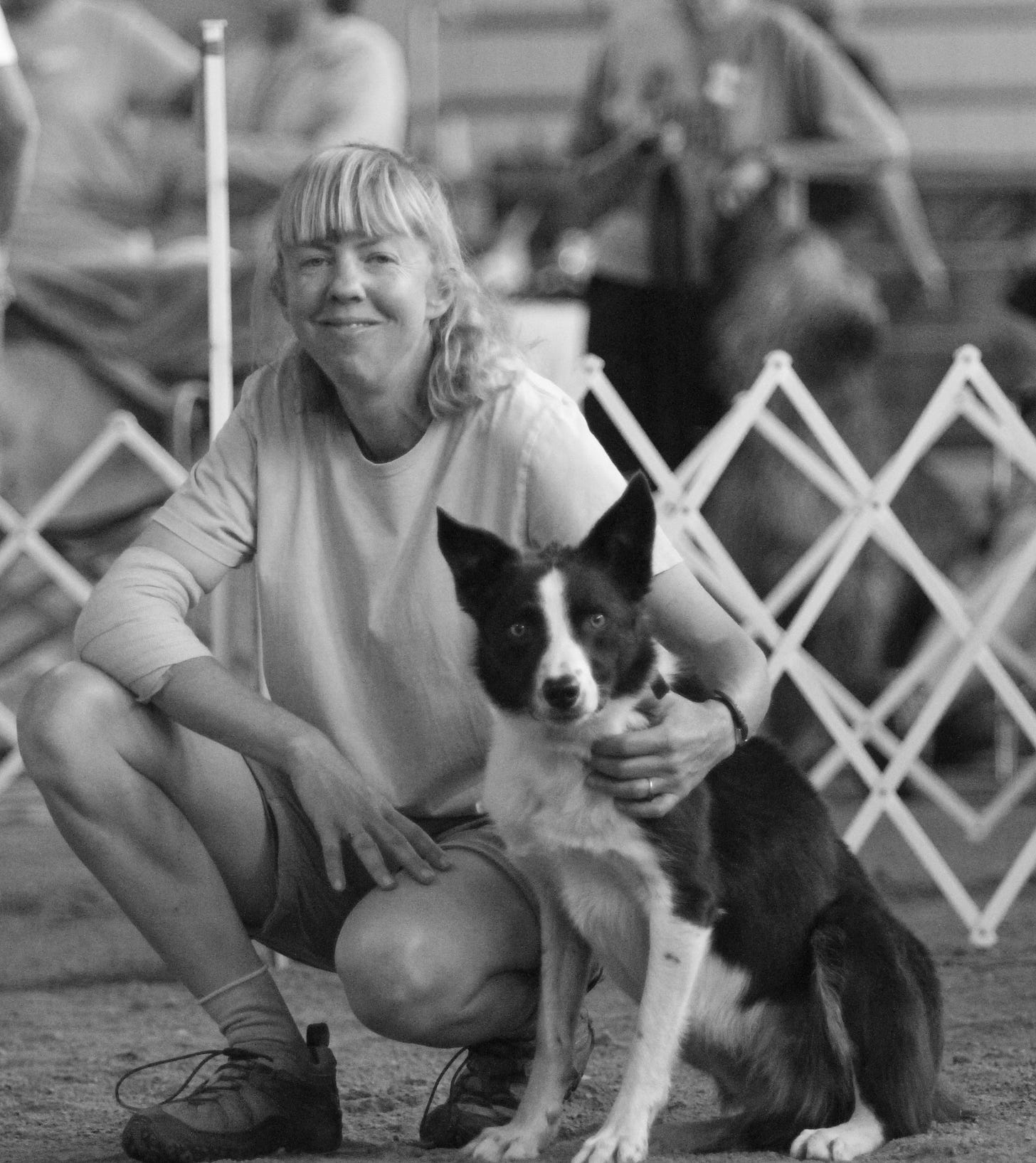 Handler & dog crouching together at the start line of an agility course