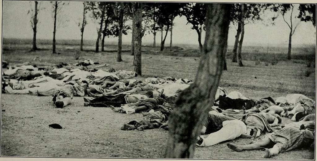 A photo of Armenian people lying dead by the roadside. There are around 20 bodies lying in a row.