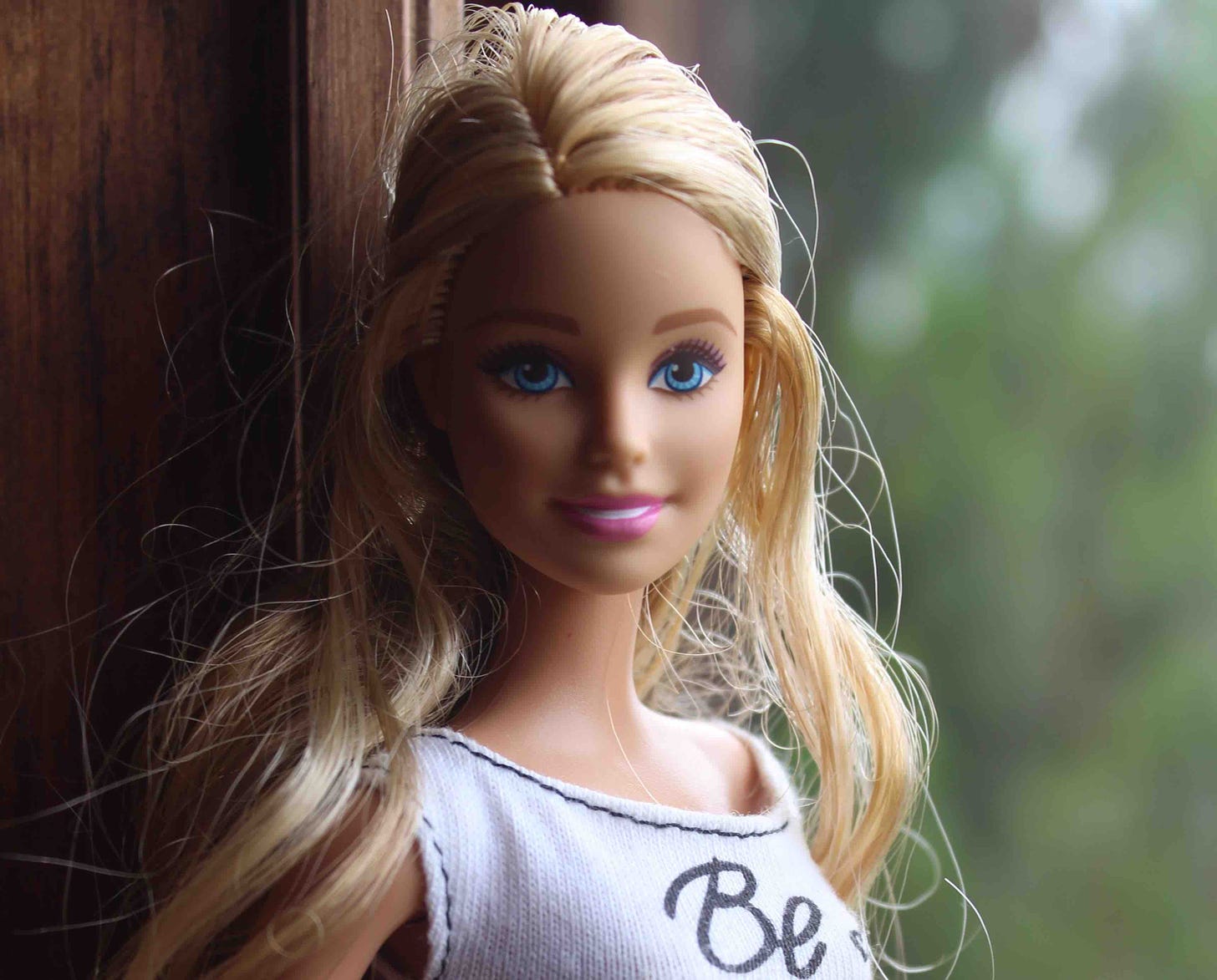 Blonde Barbie doll in front of a window