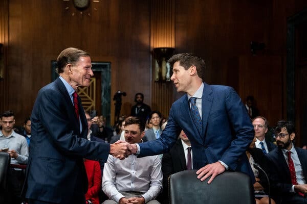 Sam Altman and Senator Richard Blumenthal, both wearing suits and ties, shake hands in a hearing room packed with people who are seated. 